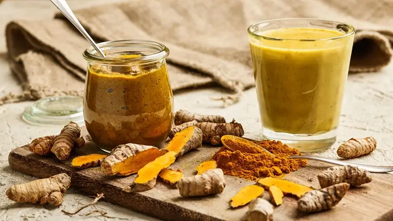 Biologische kurkumathee in glas met citroen en gember op houten tafel