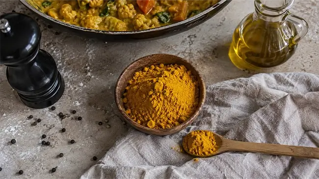 Kurkumapoeder met zwarte peper en olijfolie in de keuken, is kurkuma gezond bij de maaltijd