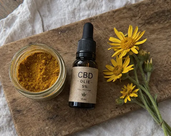 Natuurlijke ingrediënten zoals kurkuma en CBD olie op een houten tafel