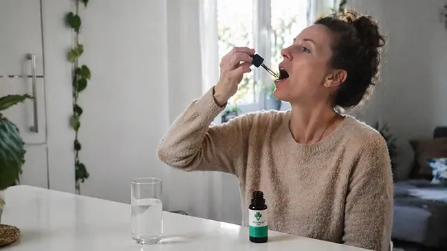 Vrouw neemt CBD olie 40 procent in met druppelaar onder de tong