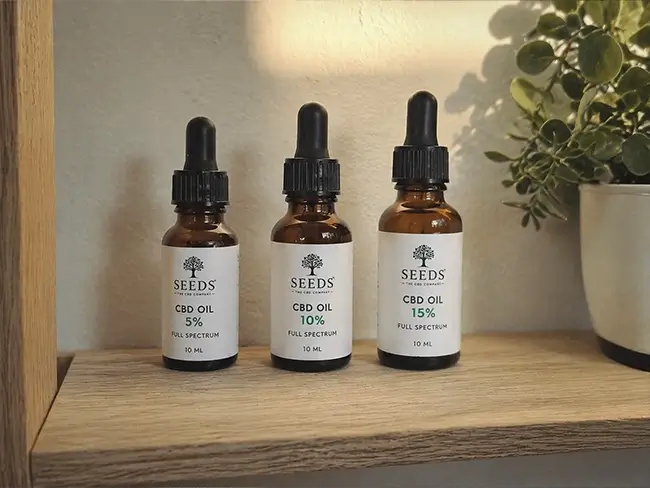 Verschillende flesjes CBD olie met uiteenlopende percentages naast elkaar op een houten tafel