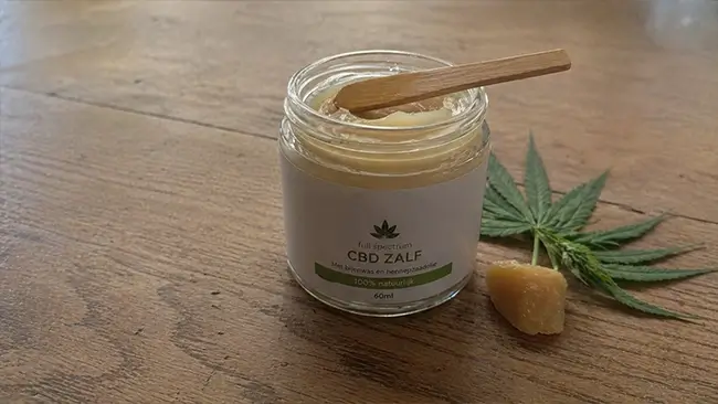 Open pot CBD zalf met bijenwas en hennepzaadolie op een houten tafel