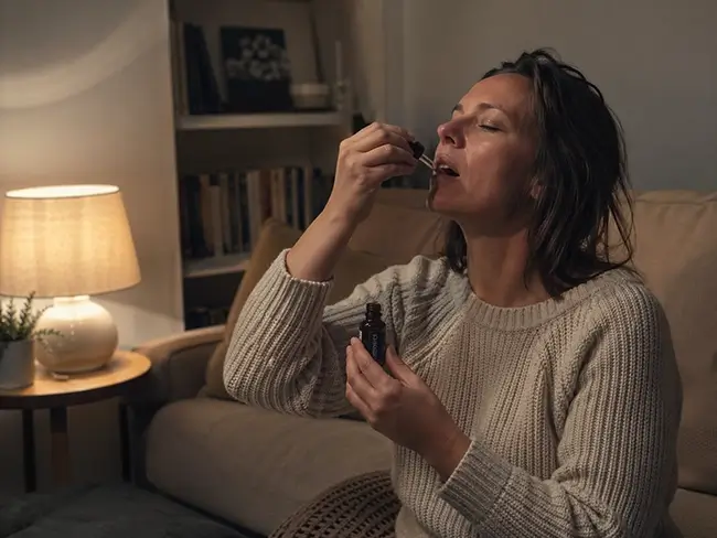 Vrouw druppelt CBG olie onder de tong als onderdeel van haar avondritueel voor beter slapen