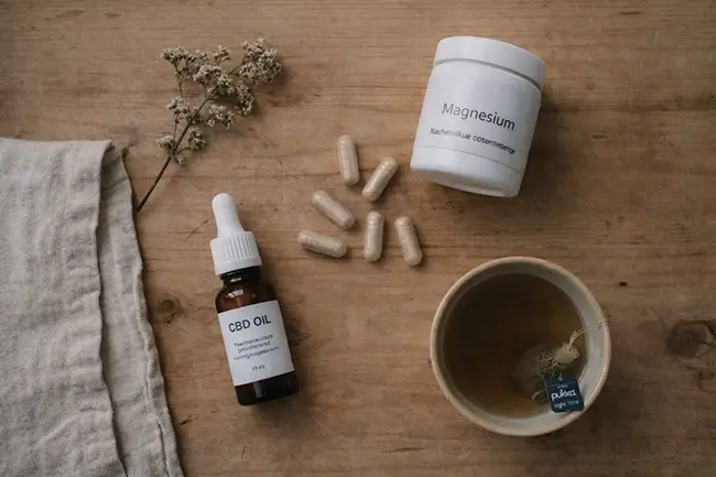 Verschillende supplementen zoals CBD olie, magnesium en ashwagandha op een houten tafel voor het slapengaan