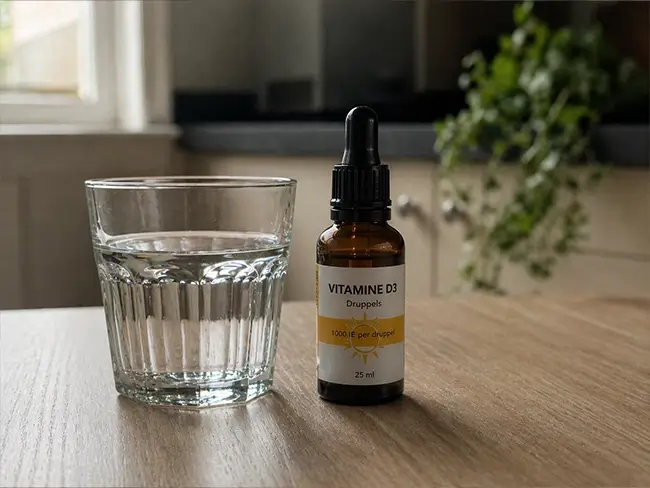 Vitamine D3 druppels naast een glas water als oplossing voor een tekort