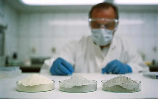 Vergelijking schone zeoliet en vervuilde zeoliet in twee glazen schaaltjes