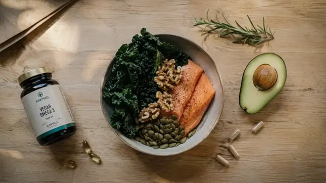 Schaal met groene bladgroenten, zalm en supplementen voor perimenopauze ondersteuning