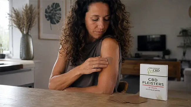 Vrouw brengt een CBD pleister aan op haar bovenarm