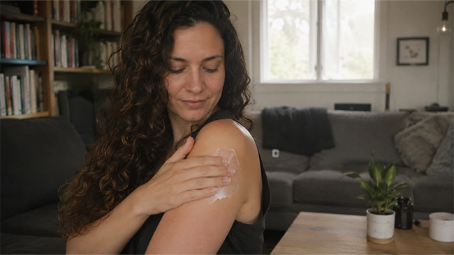 Vrouw masseert bijengifcrème in op haar schouder